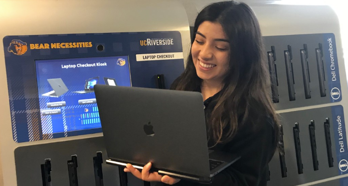 A student smiling as she works on her laptop.