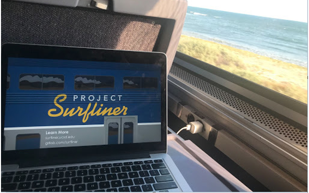 A laptop open to the surfliner website, on an Amtrak train, the Pacific Ocean is outside the window.