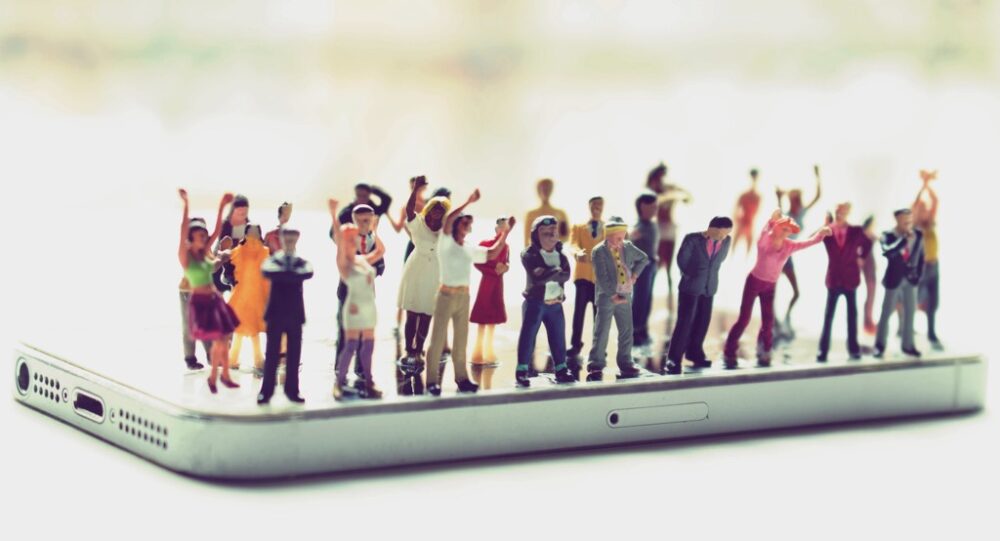 Plastic people standing on a mobile phone