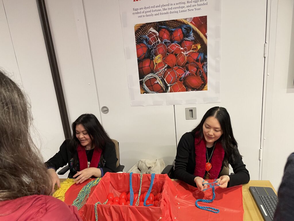 Two people preparing red eggs for the guest by weaving pieces of yarn